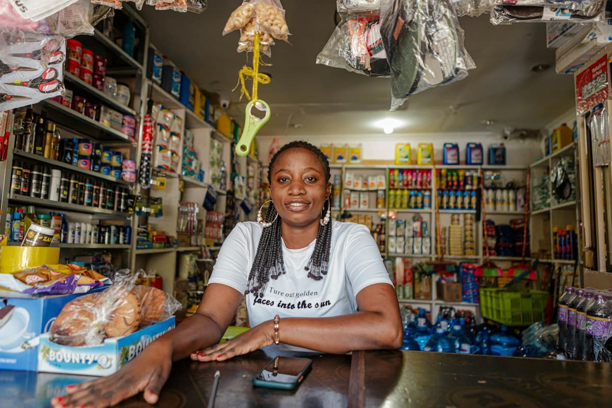 African shopkeeper with smartphone in front of stocked shelves